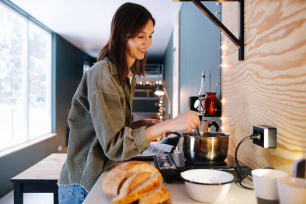 istock Smiling woman cooking on a high kitchen table, stirring soup on a stove 1322721789