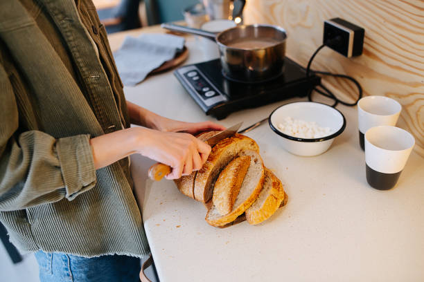 istock Woman cooking on a high kitchen table, she's cutting bread on a board. 1322721793