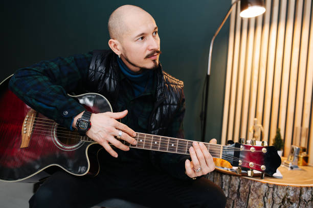 istock Bold middle aged man sitting with guitar in hands at home 1322722360