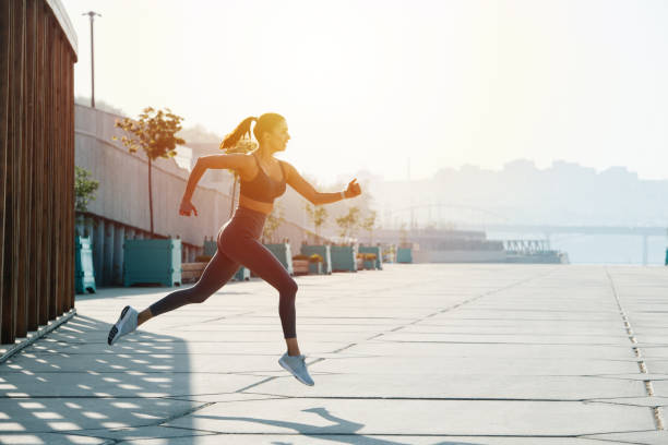 istock Side view image of a brunette running on the pavement outdoors. Low angle 1322722629