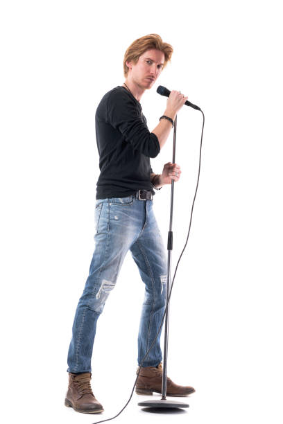 istock Profile view of cool handsome rock music singer posing with microphone on stand. 1322723886