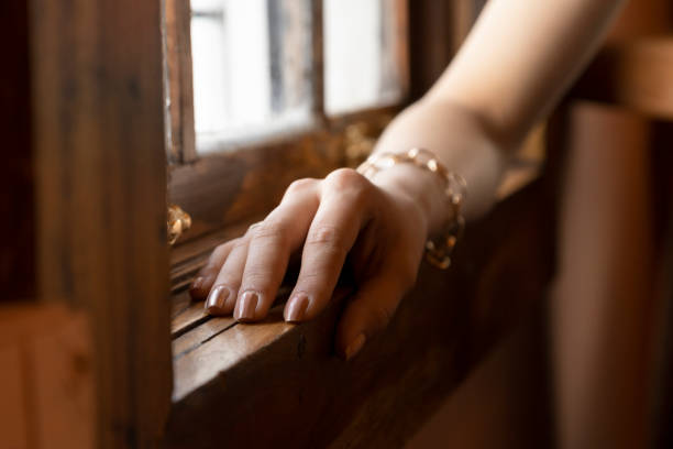 hand of a person with but elegant nails, wears a gold bracelet, the arm is close to a wooden vein, studio and parts of the body hand of a person with simple but elegant nails, wears a gold bracelet, the arm is close to a wooden vein, studio and parts of the body bijou personal accessory stock pictures, royalty-free photos & images