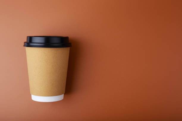 istock Flat lay with cardboard cup of coffee on brown background with copy space 1322727594
