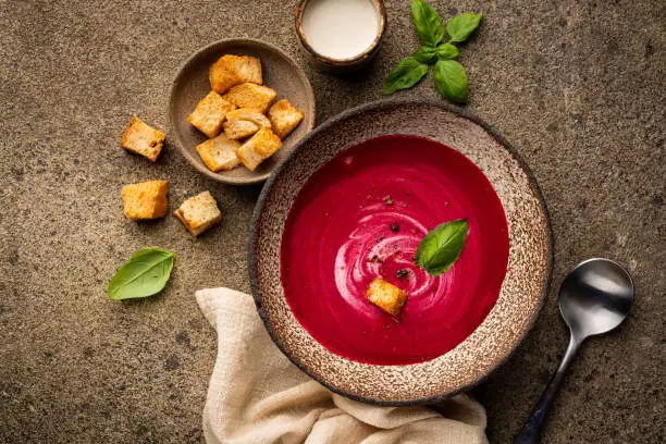Beetroot cream soup with coconut milk and croutons on a brown concrete background. Useful dietary snack and lunch. Flat lay, top view