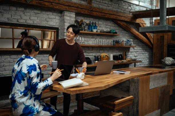 istock Japanese male bringing coffee to his partner while they working at home 1322739322