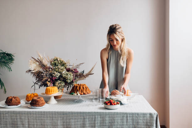 decoratore per feste: una bella donna bionda che imposta il tavolo per una festa di compleanno - dessert cake elegance food foto e immagini stock