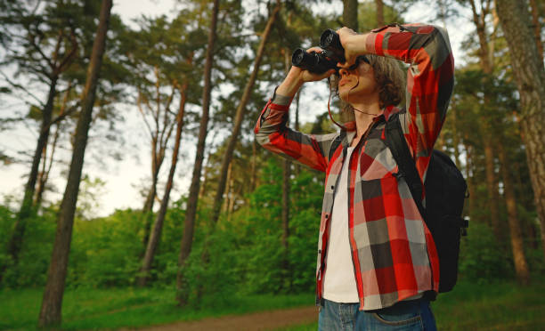 istock Man with rucksack and binoculars in the forest. 1322742381