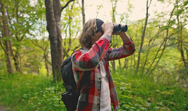 istock Man with rucksack and binoculars in the forest. 1322742398
