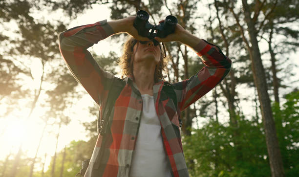 istock Man with rucksack and binoculars in the forest. 1322742400