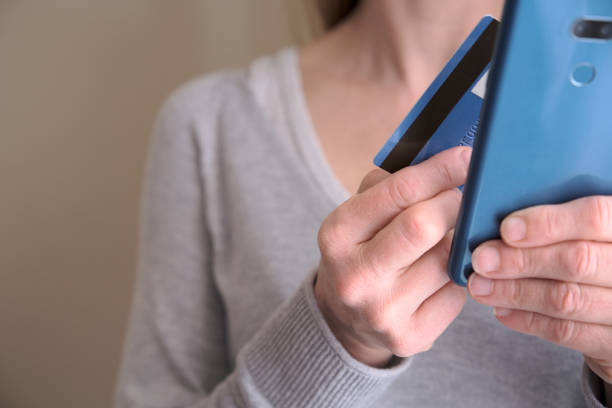 istock Online shopping concept. Female holding credit card while using her smart phone for inputting card information and making payment. Lifestyle and technology. Close up. 1322742476