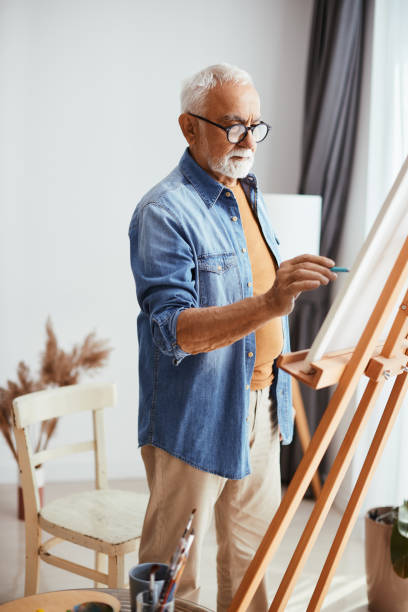 homme âgé créatif appréciant tout en peignant sur toile à la maison. - artist child artists canvas indoors photos et images de collection