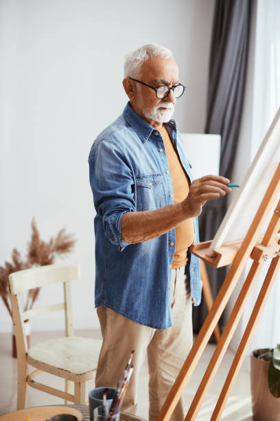 istock Creative senior man enjoying while painting on canvas at home. 1322745099