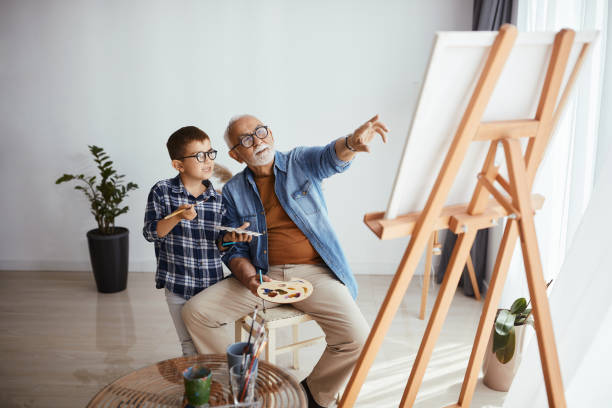 自宅で一緒に過ごしながら、孫に痛みを教える先輩男性。 - artists canvas indoors childhood small ストックフォトと画像