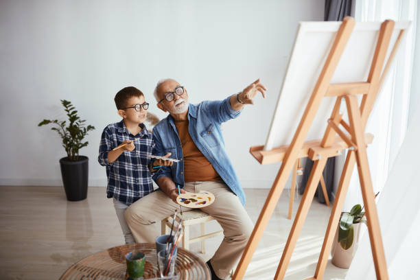 istock Senior man teaching his grandson to pain while spending time together at home. 1322745169