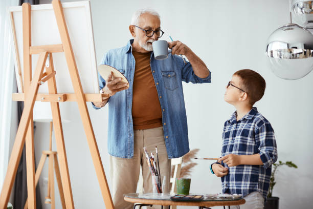 istock Grandfather and grandson talking while painting on canvas at home workshop. 1322745212