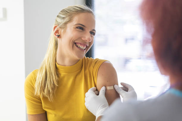 A happy patient that just received the vaccine A healthcare worker applies a bandage to a smiling patients arm. The patient has just received the flu vaccine and she appears relieved. flu vaccine photos stock pictures, royalty-free photos & images