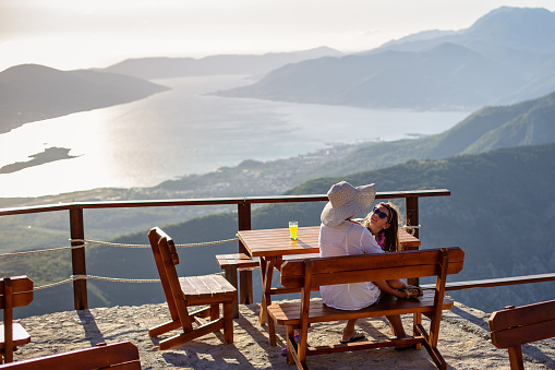 Loving grandmother and granddaughter playing and laughing together on top of view of Boka bay, Montenegro