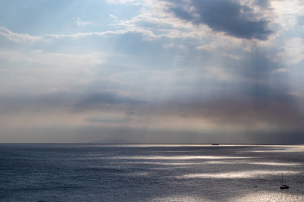 istock Sun rays shining though clouds over sea in Greece 1322755817