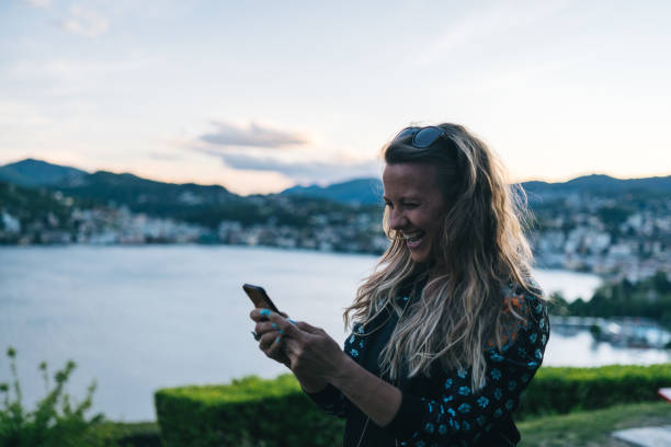 istock Young woman texts on cellphone from lakefront viewpoint 1322756902