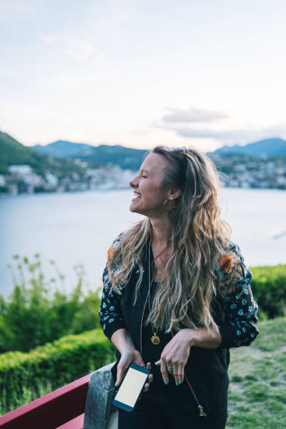istock Young woman texts on cellphone from lakefront viewpoint 1322756932