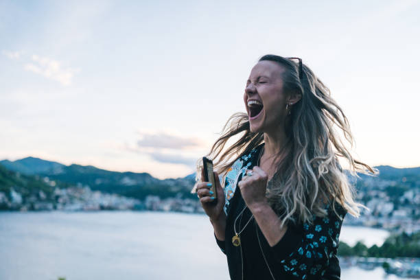 istock Young woman texts on cellphone from lakefront viewpoint 1322756934