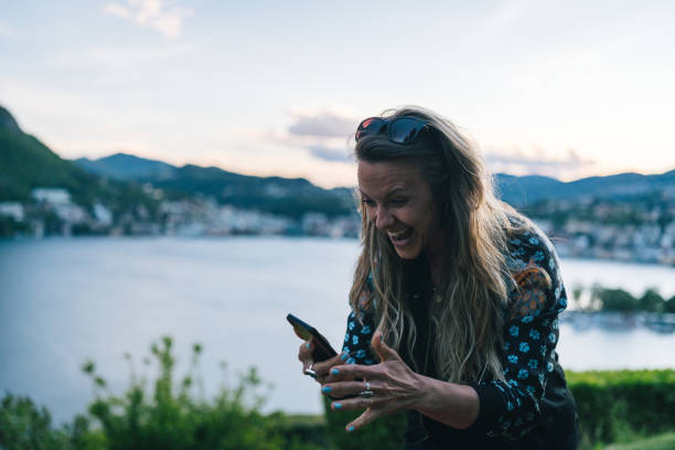 istock Young woman texts on cellphone from lakefront viewpoint 1322756935