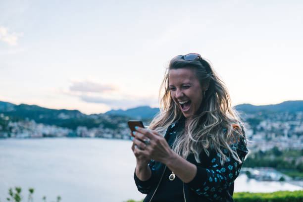 istock Young woman texts on cellphone from lakefront viewpoint 1322756992