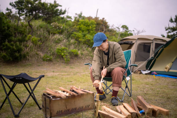 istock Young woman cutting firewood at camp 1322760401