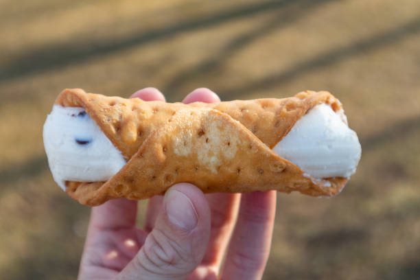 istock Delicious Traditional Cannoli Held by a Hand Outside 1322763712