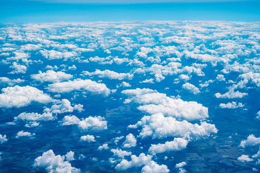 Travel concept. A beautiful view from an airplane on white voluminous fluffy clouds and blue sky. Top view.