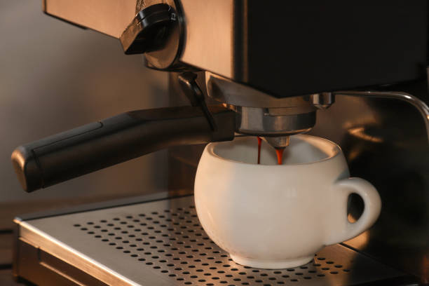 istock Medium close up, coffee in an espresso machine, in a round white cup, the essence or extract falling from the filter, appliance for a variety of caffeinated beverages, enjoyed at home or at work 1322773986