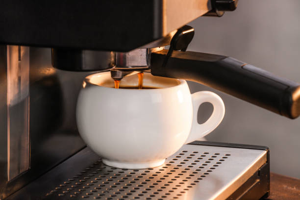 istock Medium close up, espresso machine, American coffee in a round white cup, the essence or extract falling from the filter, appliance for a variety of caffeinated beverages, hot drink served. 1322774151