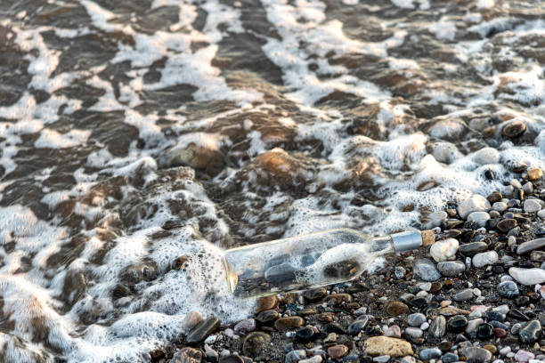 weathered empty wine bottle on pebbles by the sea - surf rescue imagens e fotografias de stock