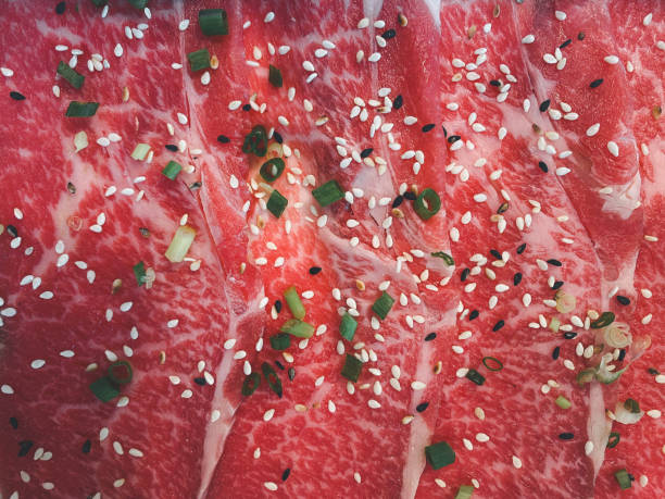 Raw freshly prepared sliced beef sprinkle black sesame seeds and white sesame seeds with sliced spring onions for barbecue (BBQ).Top view