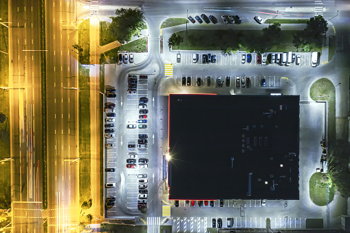 aerial top view of shopping mall with parking lot and parked cars at night time