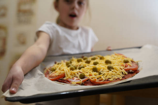 a garota segura uma assadeira preparada para assar pizza com carne. cozimento. - bread food baked 7 grain bread - fotografias e filmes do acervo