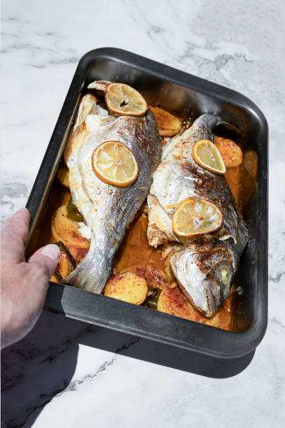istock Roasted fish and potatoes, in baking tray, ready to be served on marble background. overhead, copy space image 1322792877