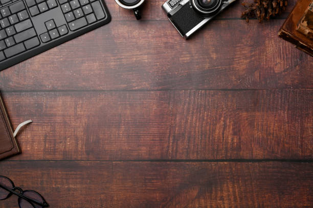 Freelancer workspace with camera, notebook, coffee cup and glasses on wooden background.
