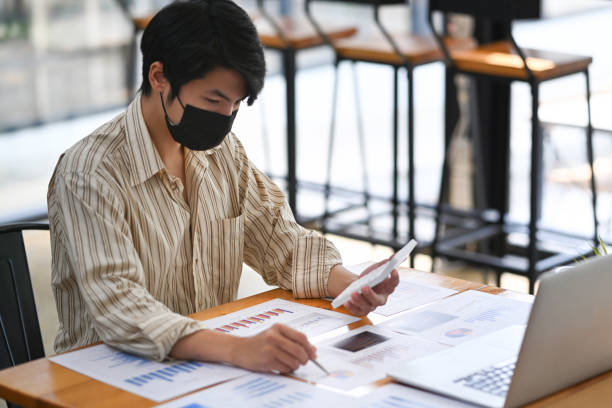 istock Businessman in face mask concentrate analyzing financial data at office desk. 1322794627