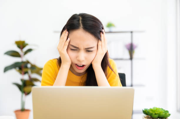 istock Asian young woman seriously working on computer laptop in house. She thinking find solution problem of work 1322796897