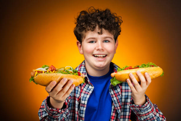 istock Boy holding two hot dogs 1322799980