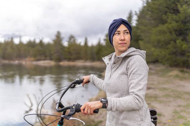 암과 싸운 후 면제된 여성은 자연 속에서 편안한 자전거를 타게 됩니다. - mental health women asian ethnicity bicycle 뉴스 사진 이미지