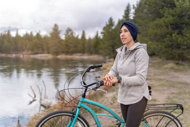 femme métisse atteinte de cancer se sent positive et pleine d’espoir lors d’une balade à vélo rajeunissante - mental health women asian ethnicity bicycle photos et images de collection