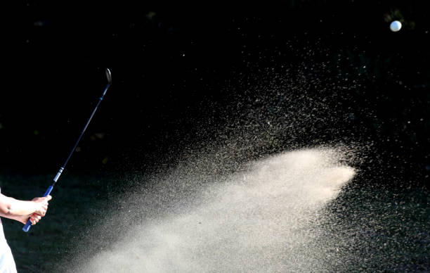 알아볼 수 없는 여성 골퍼가 그린 사이드 벙커에서 샷을 날고 있다. - golf golfer examining wind 뉴스 사진 이미지