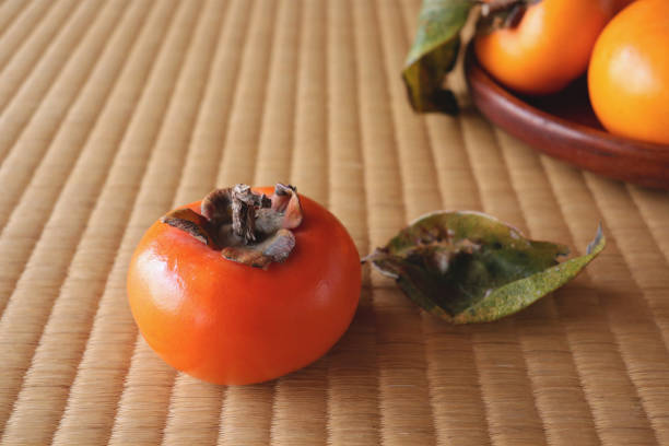 istock A persimmon on the tatami mat and persimmons on a wooden flat plate. 1322802466