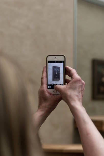 the mona lisa as seen through a tourist's smartphone at the louvre museum. - mona lisa imagens e fotografias de stock