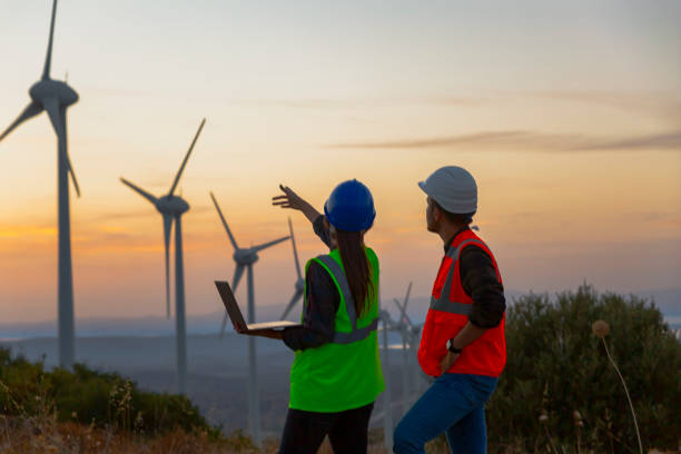 joven equipo de ingenieros de mantenimiento trabajando en un parque de turbinas eólicas al atardecer - maintenance engineer fotografías e imágenes de stock