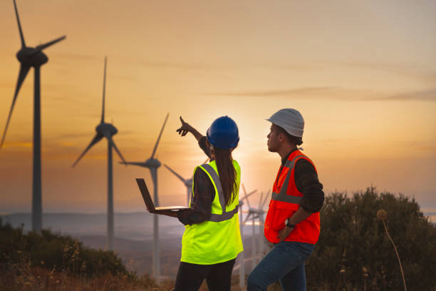istock Young maintenance engineer team working in wind turbine farm at sunset 1322805606