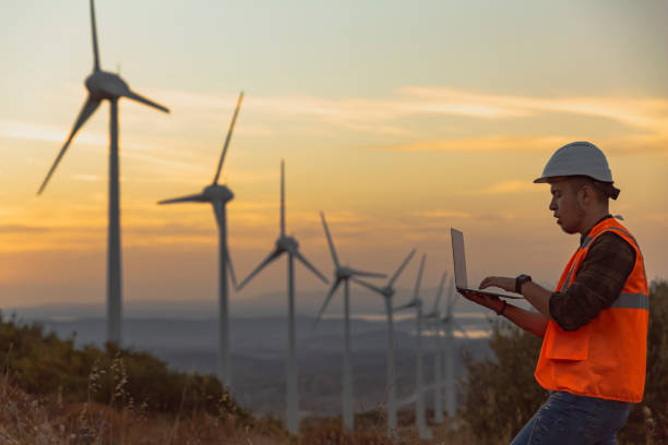 istock Young maintenance engineer man working in wind turbine farm at sunset 1322805617