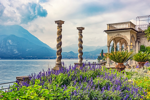 Tourist looking at lake by mountain while standing by flower pots at public park during sunny day